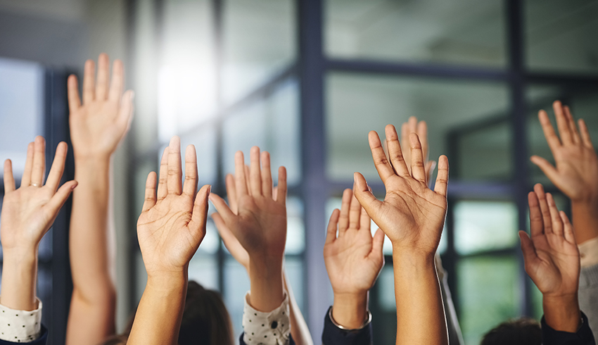 Many hands raised in the air to ask a question